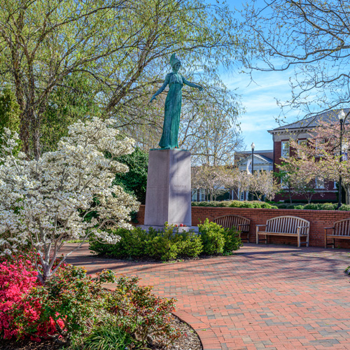 UNCG Minerva statue with spring flowers.