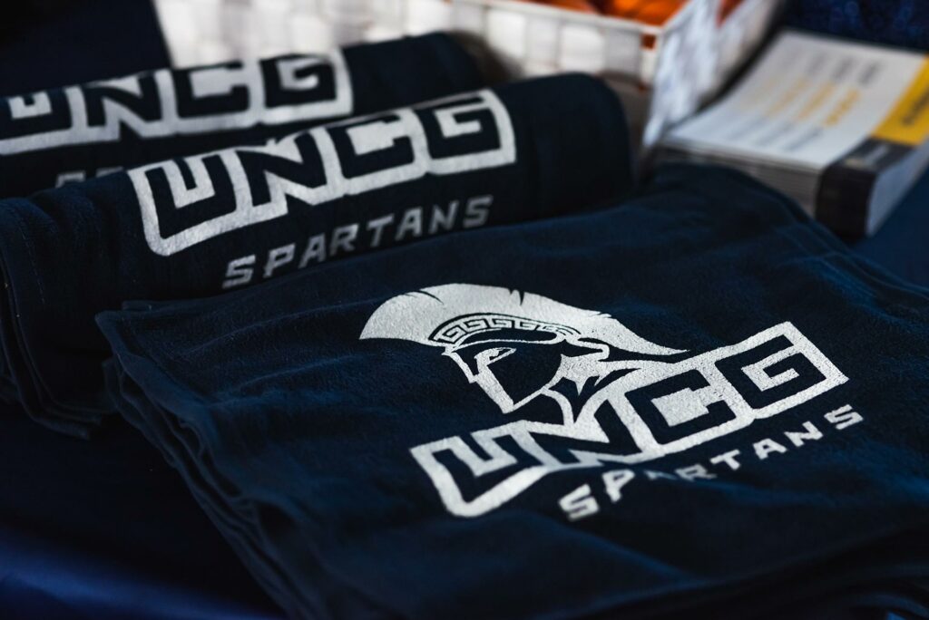 Stack of T-shirts showing UNCG logo "UNCG Spartans"